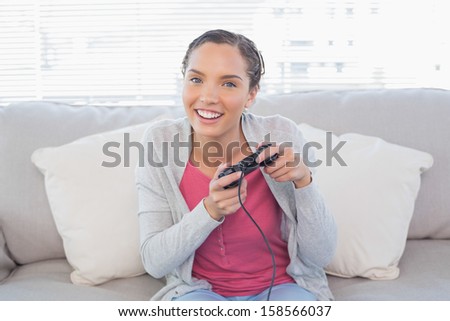Happy woman sitting on sofa in bright living room playing video games