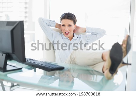 Pleased stylish brunette businesswoman relaxing with feet up in bright office