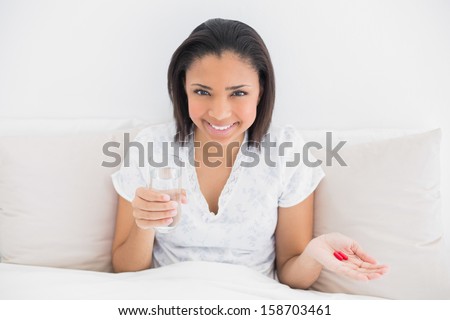 Content young dark haired model taking medication in bright bedroom