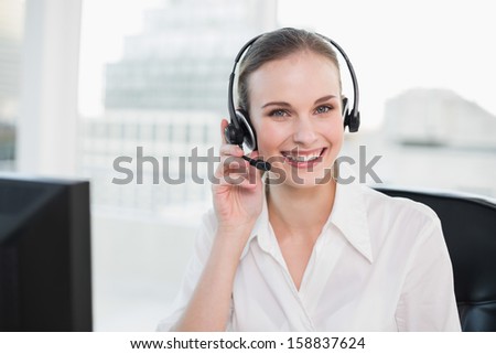 Happy call center agent looking at camera in her office