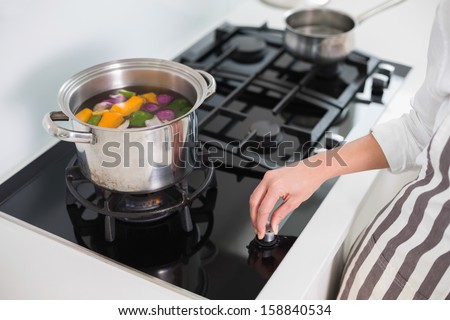 Close up on woman cooking vegetables in bright kitchen