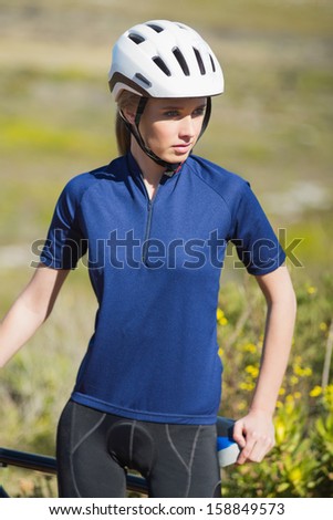 Serious woman with bike wearing helmet looking away