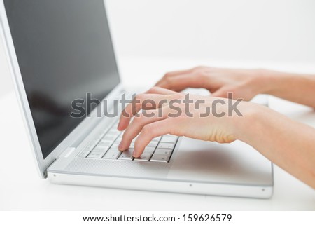Close-up of hands typing on laptop keyboard over white background