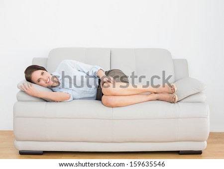 Portrait of a smiling well dressed young woman relaxing on sofa at home