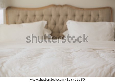 Empty bed with white duvet cover in bright bedroom