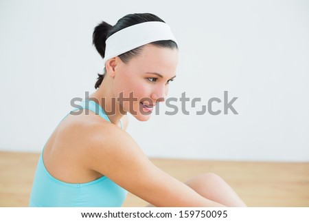 Close-up side view of a thoughtful toned woman in fitness studio