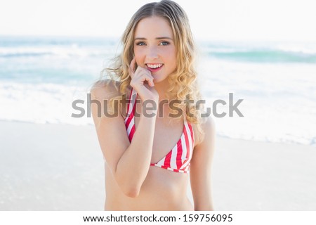 Beautiful young woman posing on the beach wearing a red bikini