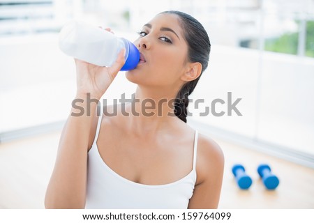 Calm toned brunette sitting on floor drinking in bright room