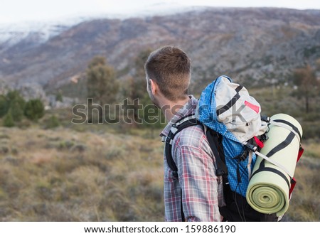 Side view of a fit young man with backpack standing on forest landscape