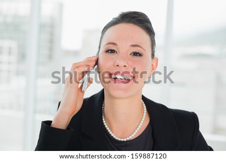 Close-up portrait of a smiling elegant businesswoman using cellphone in bright office