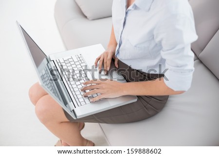 High angle view of a well dressed young woman using laptop on sofa at home