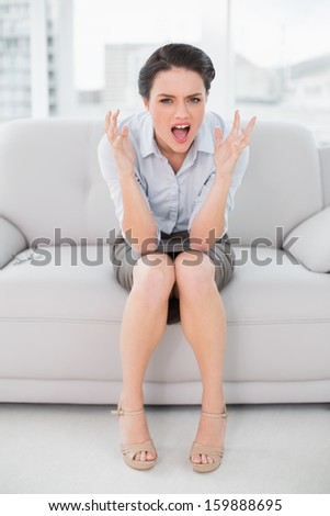 Full length portrait of an elegant young woman shouting in anger at home