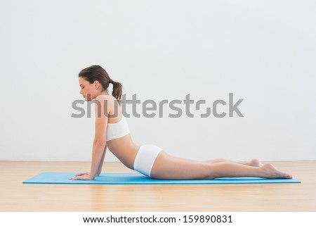 Side view of young woman doing the cobra pose on exercise mat
