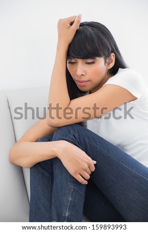 Thoughtful casual woman sitting on couch in bright living room