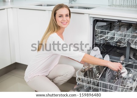 Smiling Gorgeous Model Kneeling Next To Dish Washer In Bright Kitchen