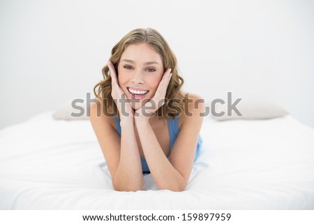 Cheerful pretty woman laughing at camera while lying on her bed in her bedroom
