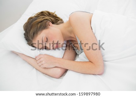 Beautiful peaceful woman napping under the cover on her bed in the bedroom