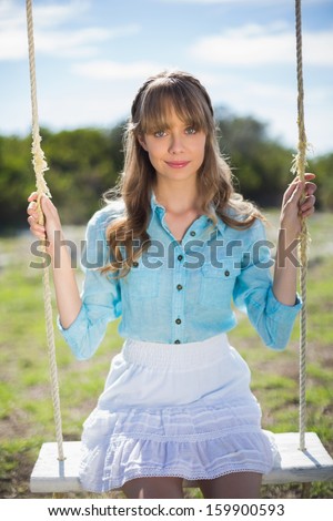 Peaceful young model relaxing in a sunny garden while sitting on swing
