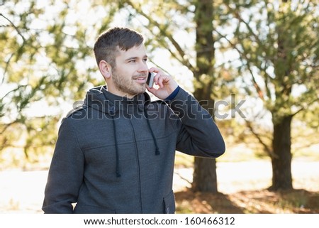 Smiling young man using mobile phone in the forest