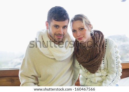 Portrait of a young couple in winter clothing sitting against window