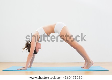 Full length side view of a sporty young woman doing the Downward Facing Dog pose on exercise mat