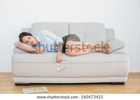 Full length of a well dressed young woman sleeping on sofa at home