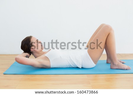 Full length side view of young woman lying with hands behind head on mat