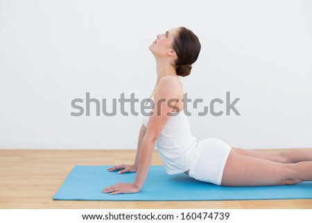 Side view of young woman doing the cobra pose on exercise mat
