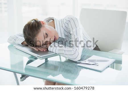 Tired young businesswoman sleeping in her office sitting at her desk