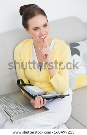 Thoughtful Young Woman With Personal Organizer And Laptop At Home