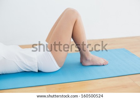 Side view low section of sporty young woman lying on exercise mat