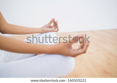 Mid section of slender young woman meditating sitting in lotus position