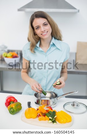 Lovely smiling woman cooking standing in kitchen smiling cheerfully at camera