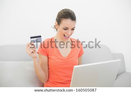 Happy calm woman home shopping with her laptop sitting on couch