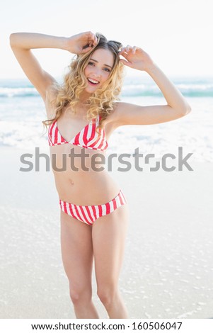 Cheerful young woman dancing on the beach wearing a red bikini