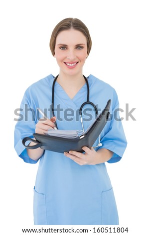 Female doctor writing into file while smiling into the camera on white background