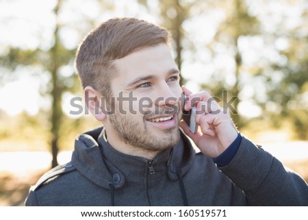 Close-up of a smiling young man using mobile phone in the forest