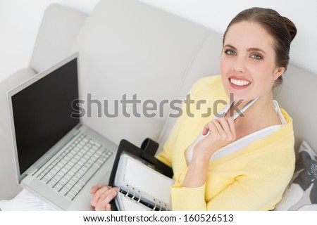 Portrait of a young woman with personal organizer and laptop at home