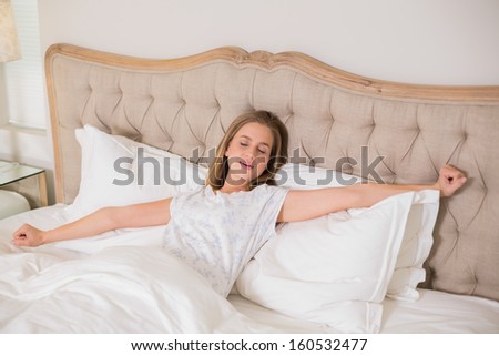 Natural frowning woman yawning and resting in bed in bright bedroom