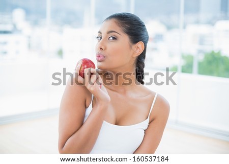 Calm toned brunette holding apple in bright room