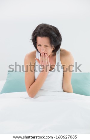 Young woman yawning in bed with eyes closed