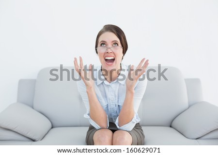 Displeased well dressed young woman screaming on sofa at home