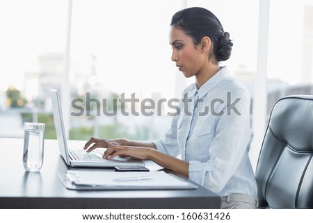 Young attentively working businesswoman sitting at her desk in the office