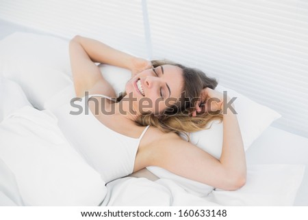 Lovely exhausted woman lying on her bed stretching out with eyes closed