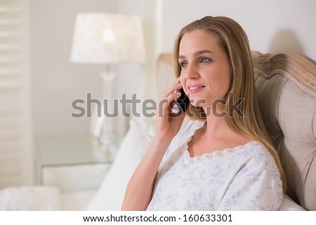 Natural calm woman sitting in bed phoning in bright bedroom