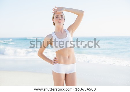 Tired slender woman touching her forehead standing on the beach