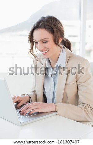 Smiling young businesswoman using laptop in a bright office