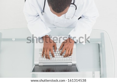Overhead view of a male doctor using laptop at medical office