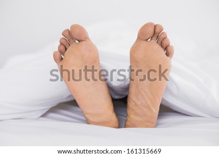 Close up of bare feet in bed at home