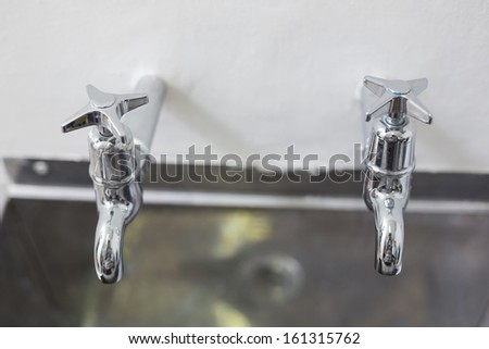 Close up of two taps and stainless steel kitchen sink